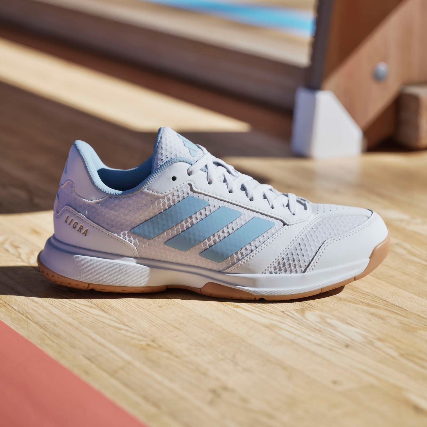 White and blue adidas shoe with the word Ligra on a squash court