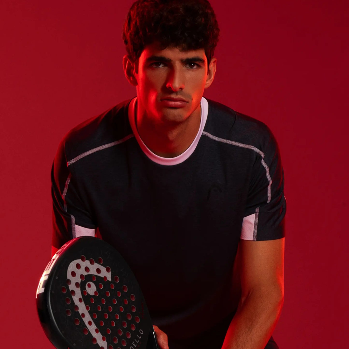 Man holding a padel racket against a red background