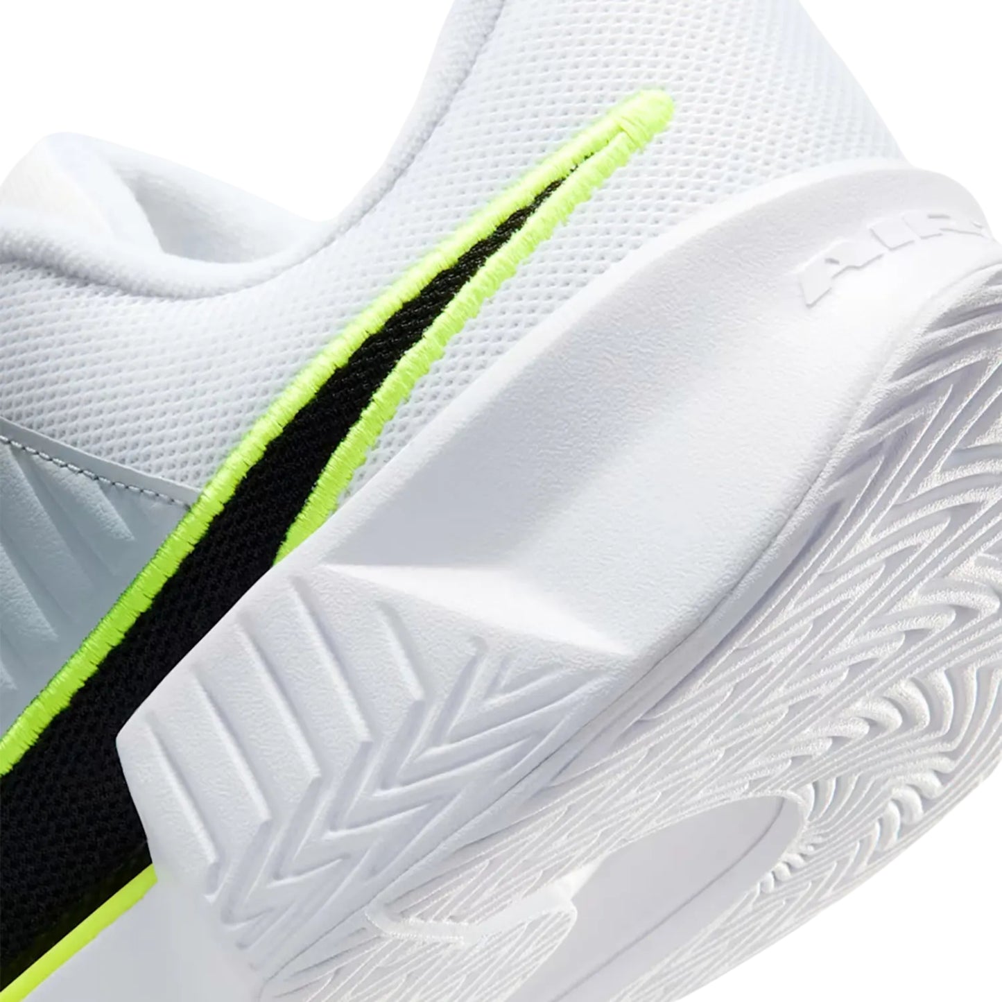 Close-up of a white tennis shoe with black and green accents on a white background