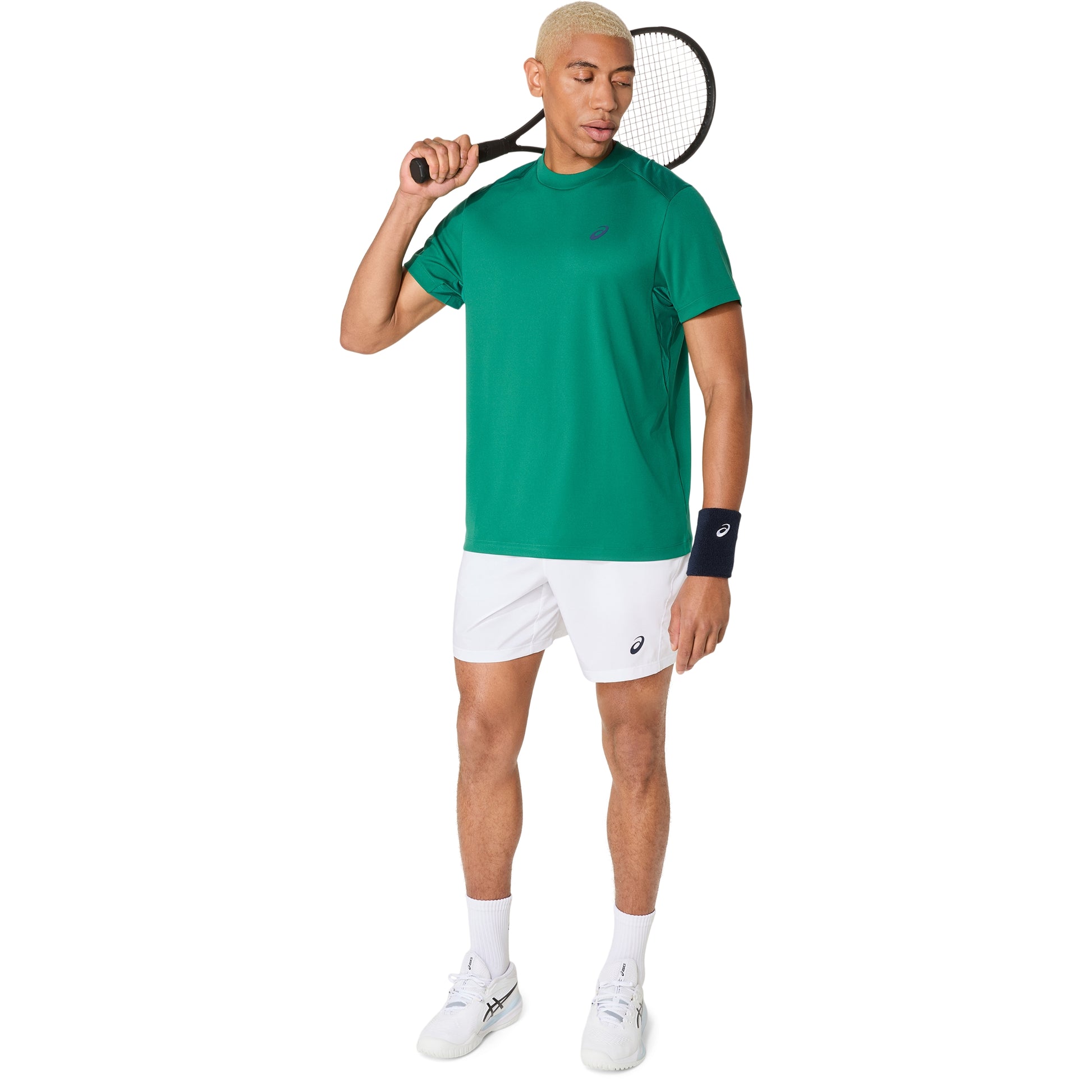 Man in green shirt and white shorts holding a tennis racket on a white background