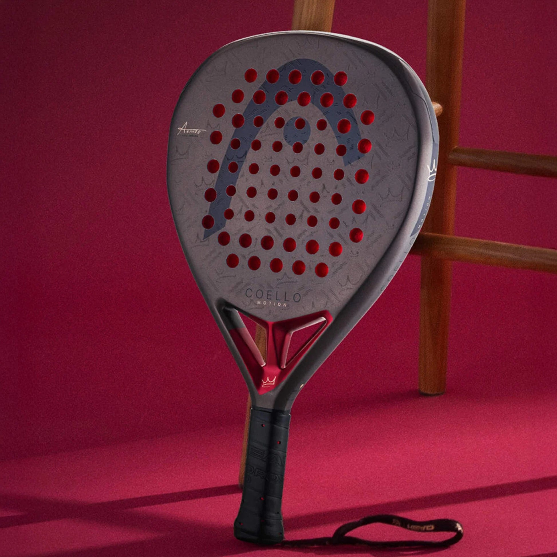 Padel racket with red and black design on a pink background