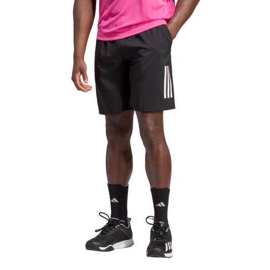 Person wearing black Adidas shorts and shoes on a white background