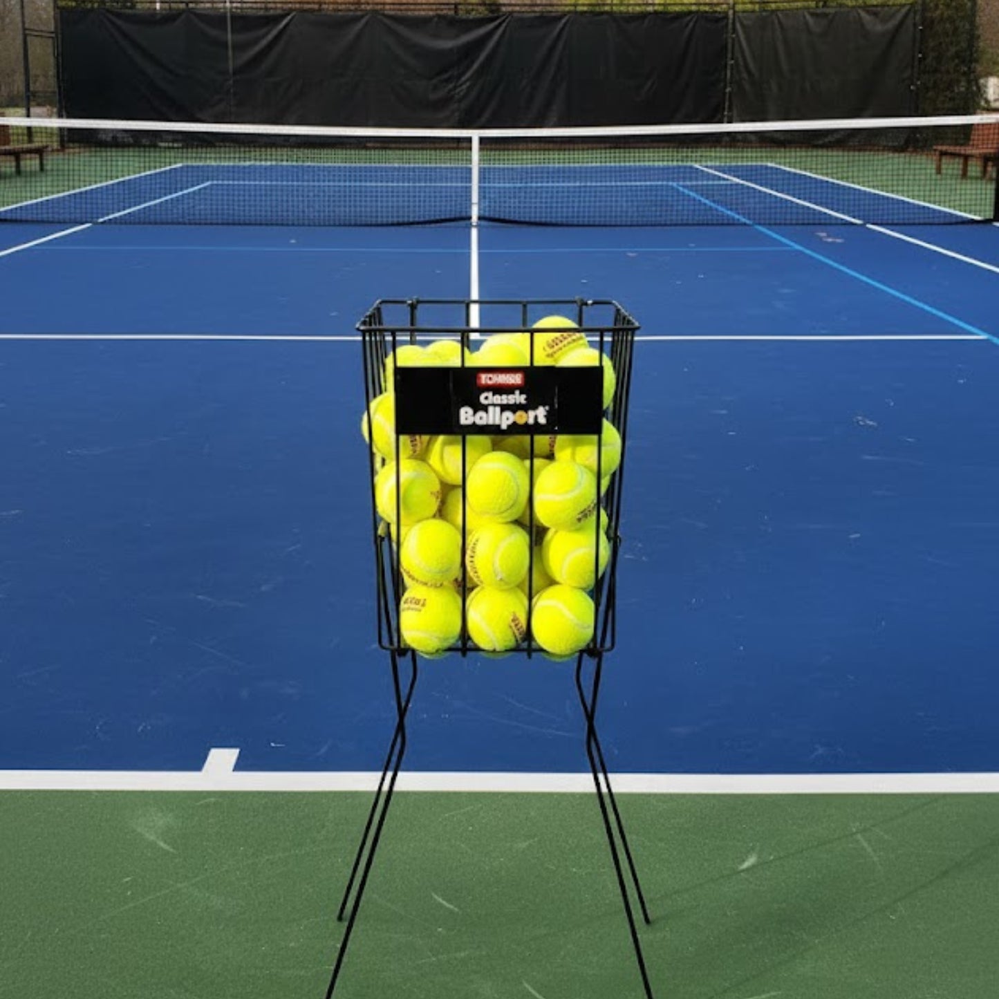 Tennis ball basket on a tennis court with a black background