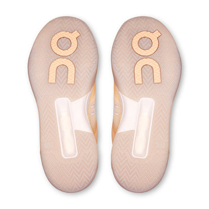 Top-down view of a pair of On shoe soles in a pale peach-beige color with a chevron pattern and a large metallic gold 'on' logo on each.