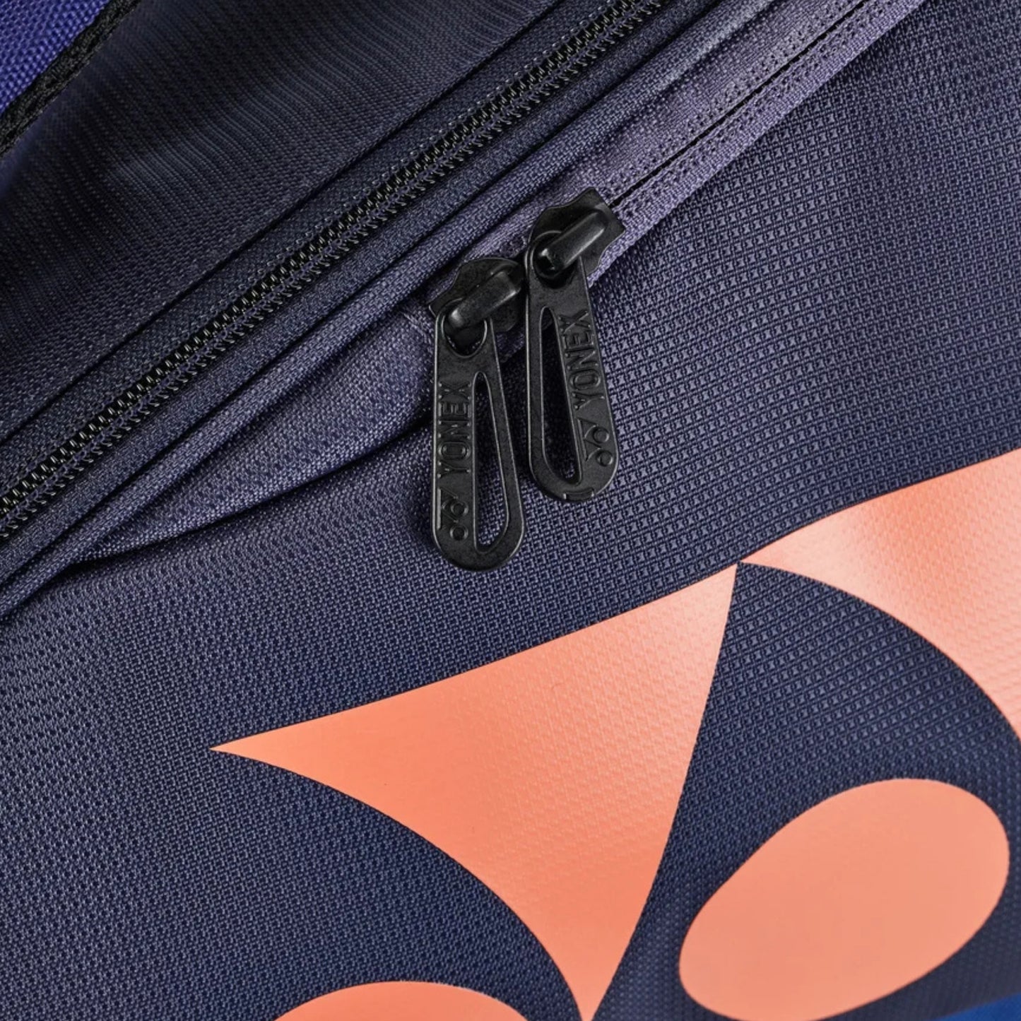 Navy blue Yonex bag with orange geometric patterns and black zippers.
