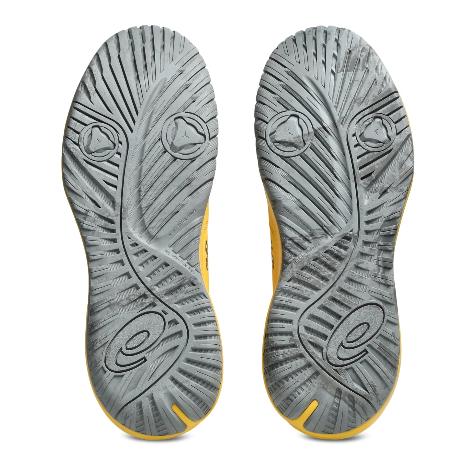 The outsoles of a pair of Asics tennis shoes, showing a textured gray design with yellow accents along the edges, photographed against a solid white background.