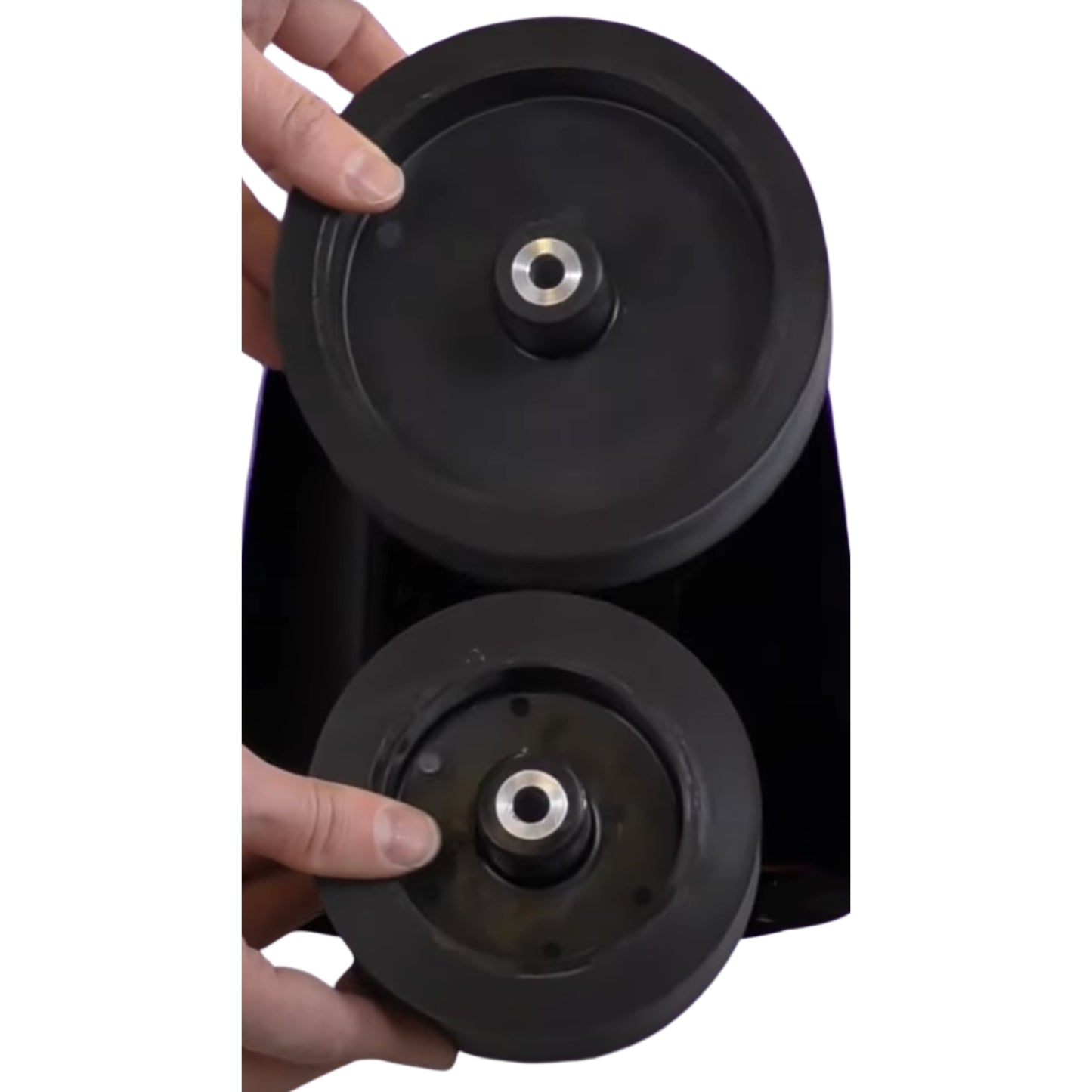 Close-up of a black wheel assembly held by a hand on a white background