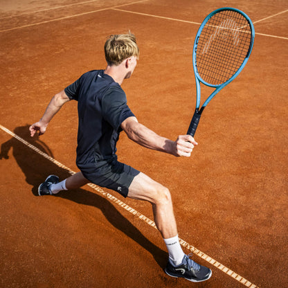 Tennis player in action on a clay court with a blue racket