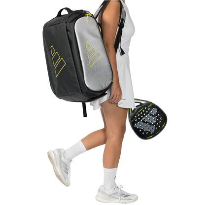 Person holding a black and gray sports bag with a yellow logo on a white background