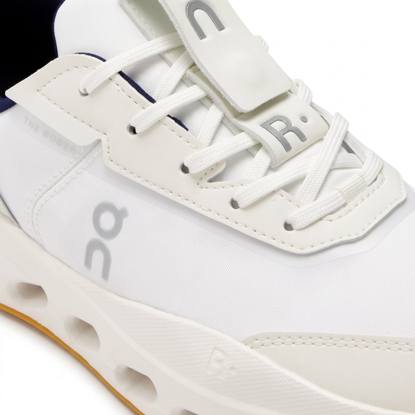 Close-up of a white On tennis shoe with white laces, a white midsole, and light gray logo details, set against a clean white background.