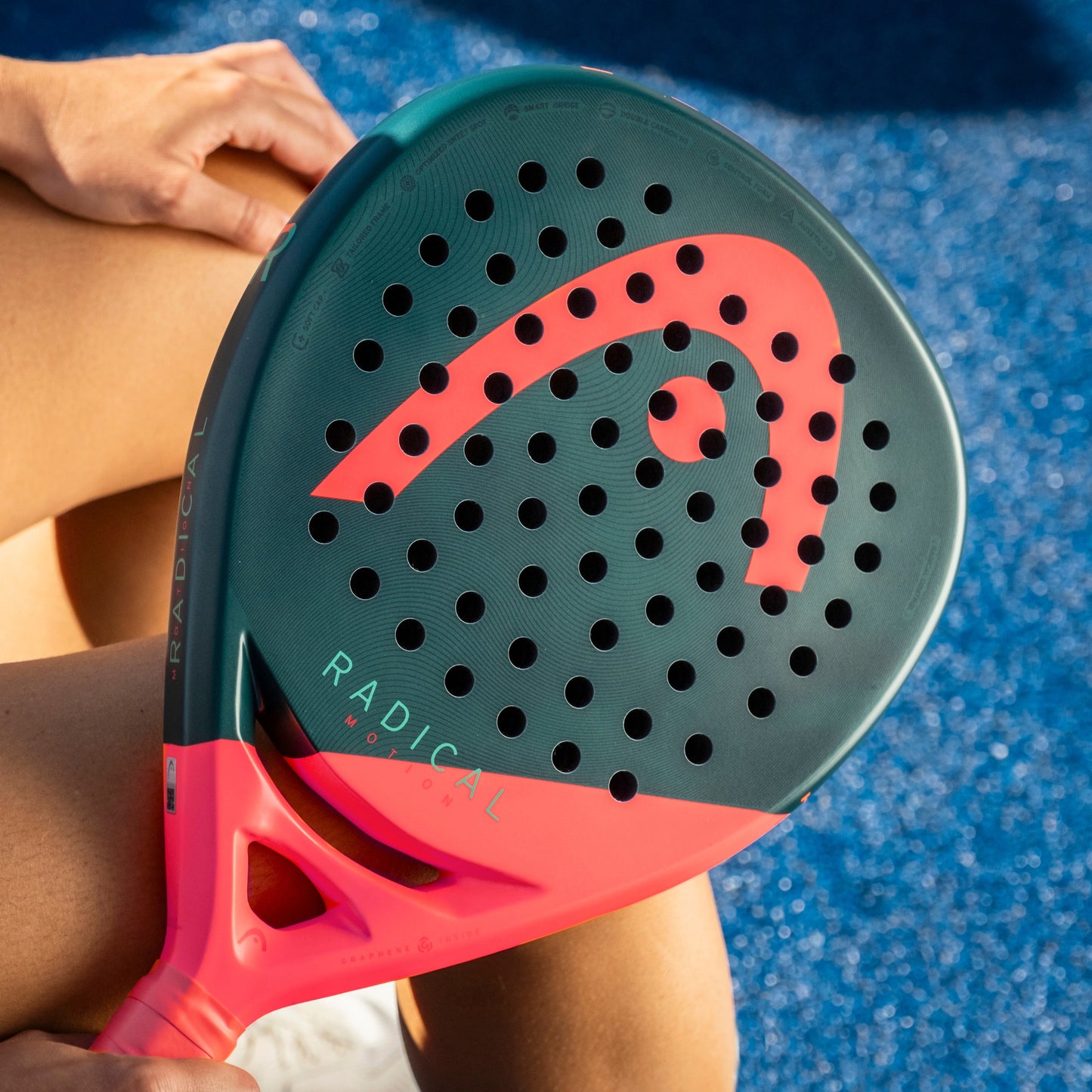 Person holding a green and red paddle with 'Radical' branding on a blue surface