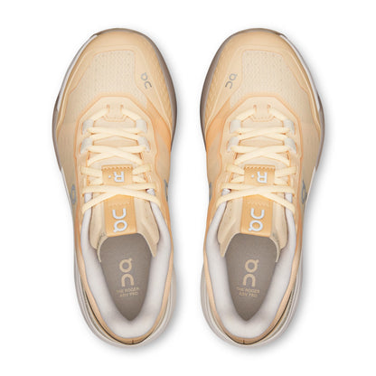 A pair of On running shoes in a light peach and cream colorway, shown from a top-down view on a white background.