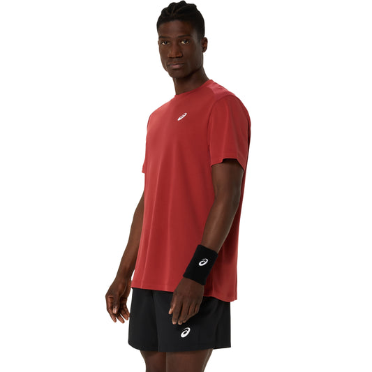 Man wearing a red athletic shirt and black shorts with a Asics brand logo on a white background