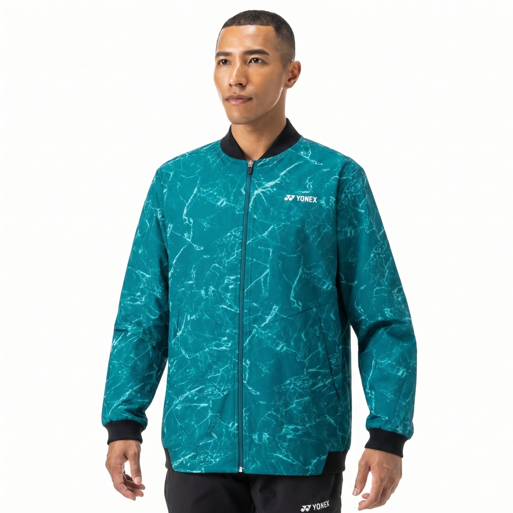 Man wearing a teal patterned jacket with Yonex logo on a white background