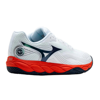 A white Mizuno tennis shoe with a prominent orange midsole, dark navy logo and outsole, and a small green accent on the heel.