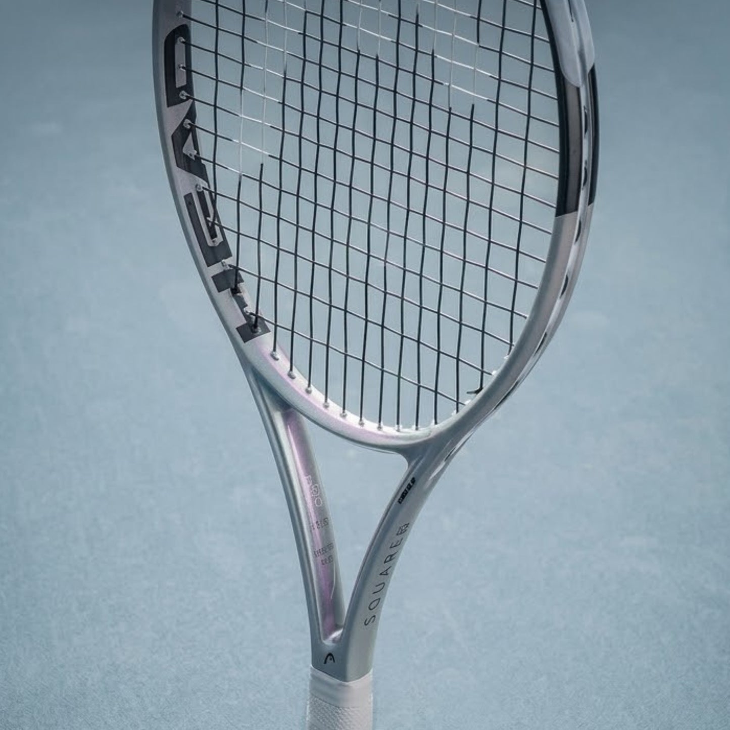Silver tennis racket with 'HEAD' branding on a light blue background