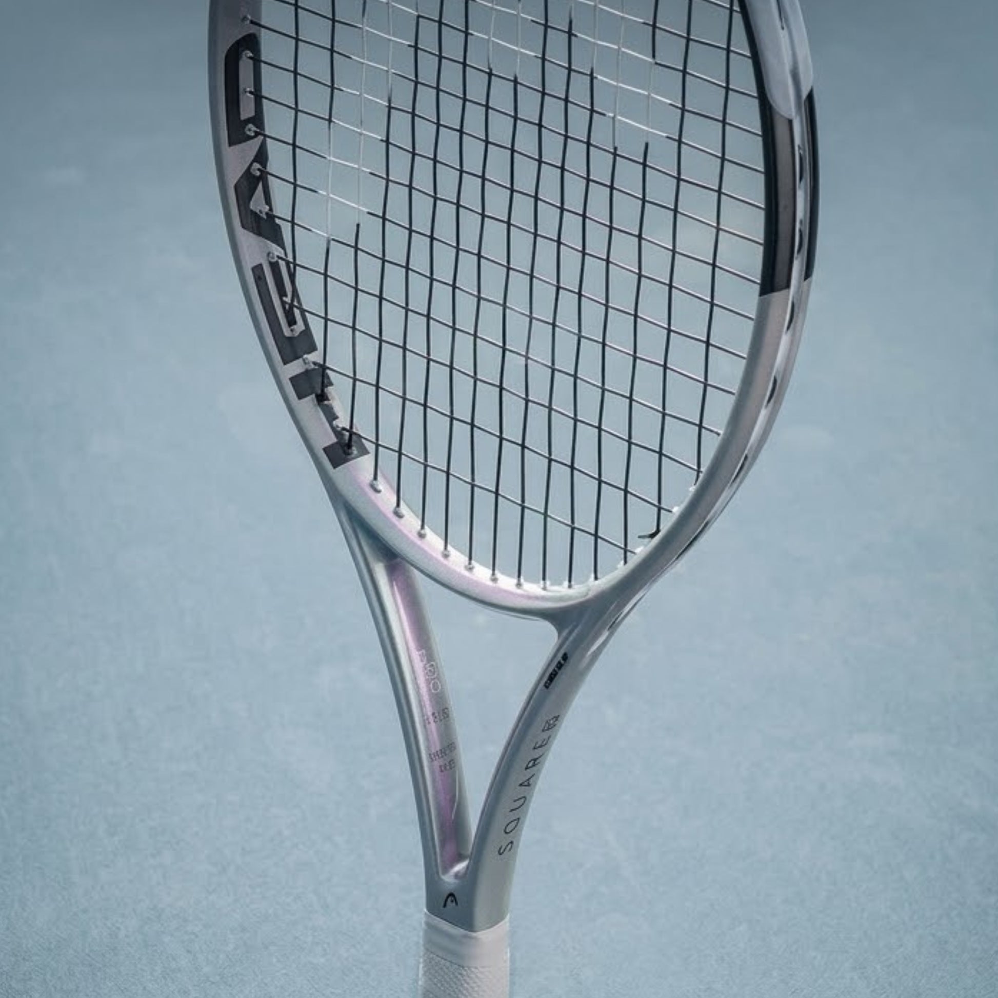 Silver tennis racket with 'HEAD' branding on a light blue background