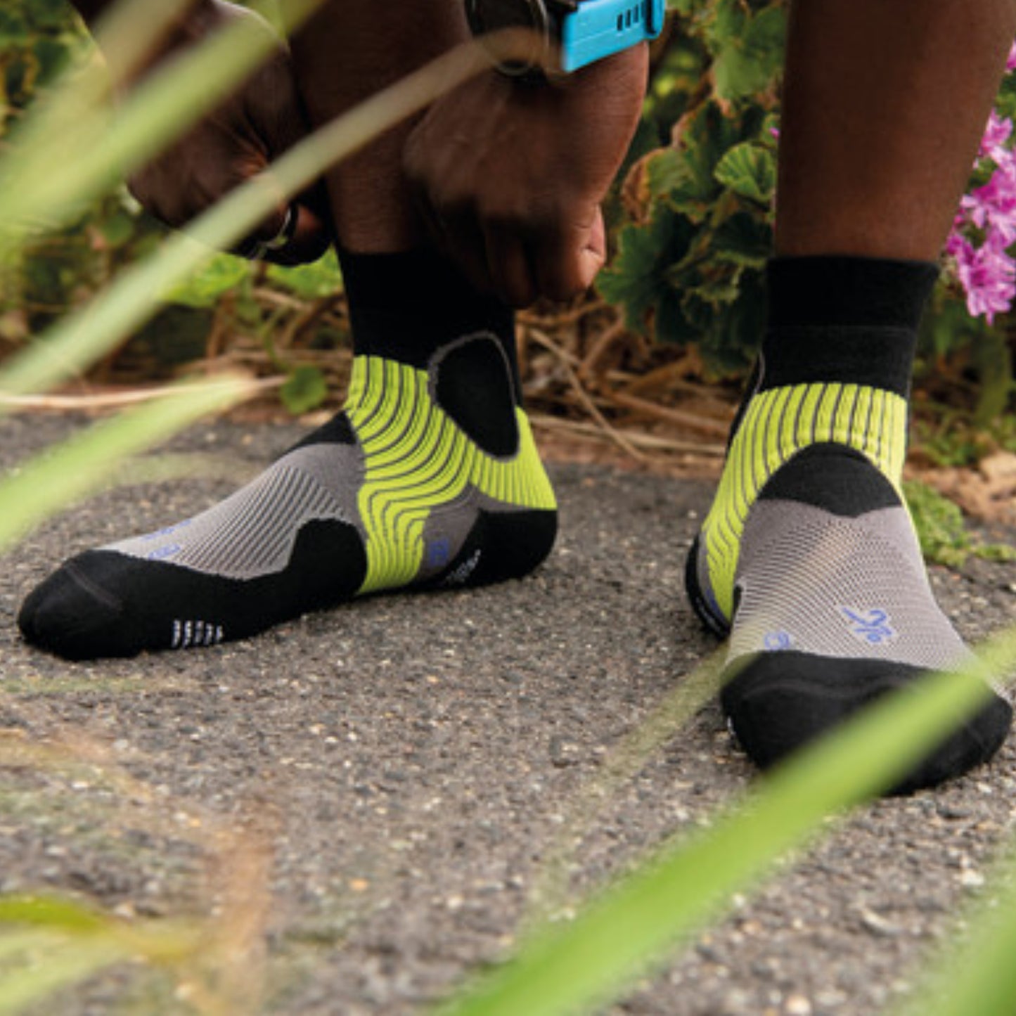 Person wearing black and gray socks with yellow accents on a path.