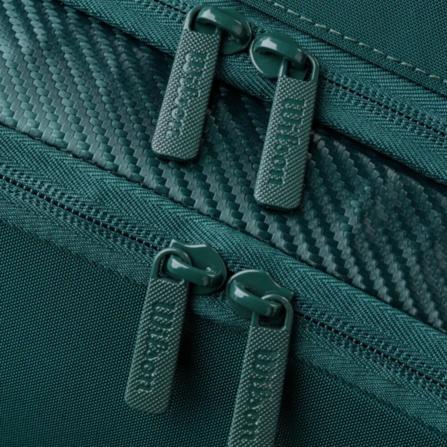 Close-up of green zippers on a textured fabric surface