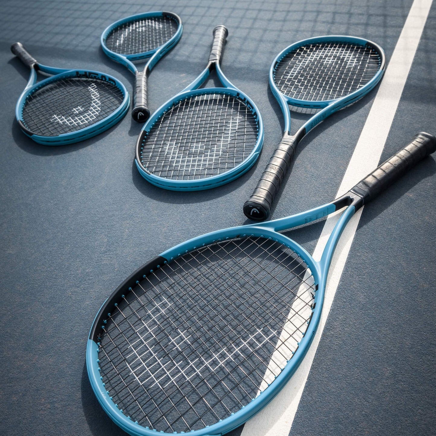 Five blue Head tennis rackets on a dark surface