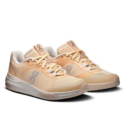 A pair of On running shoes in a warm peach and beige colorway, featuring the brand's signature 'on' logo on the side and tongue, set against a clean white background.