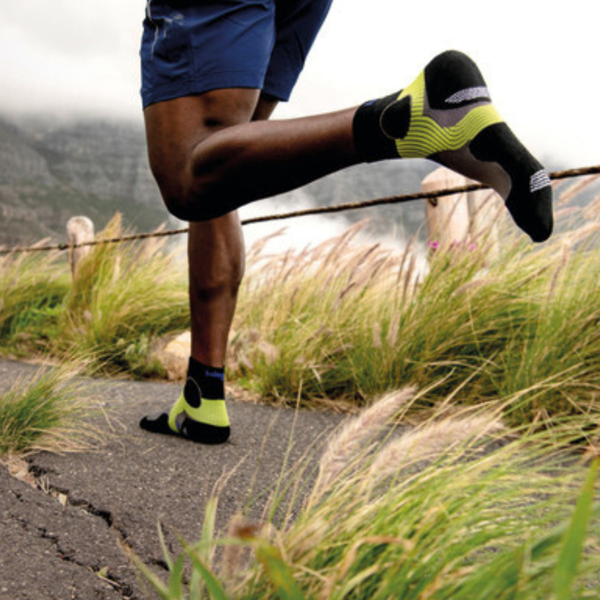 Person running on a trail wearing black and yellow socks
