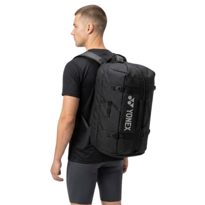 Man wearing a black Yonex backpack on a white background