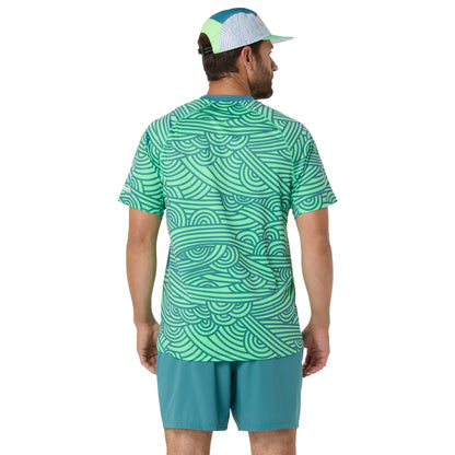 Man wearing a green patterned shirt and teal shorts on a white background
