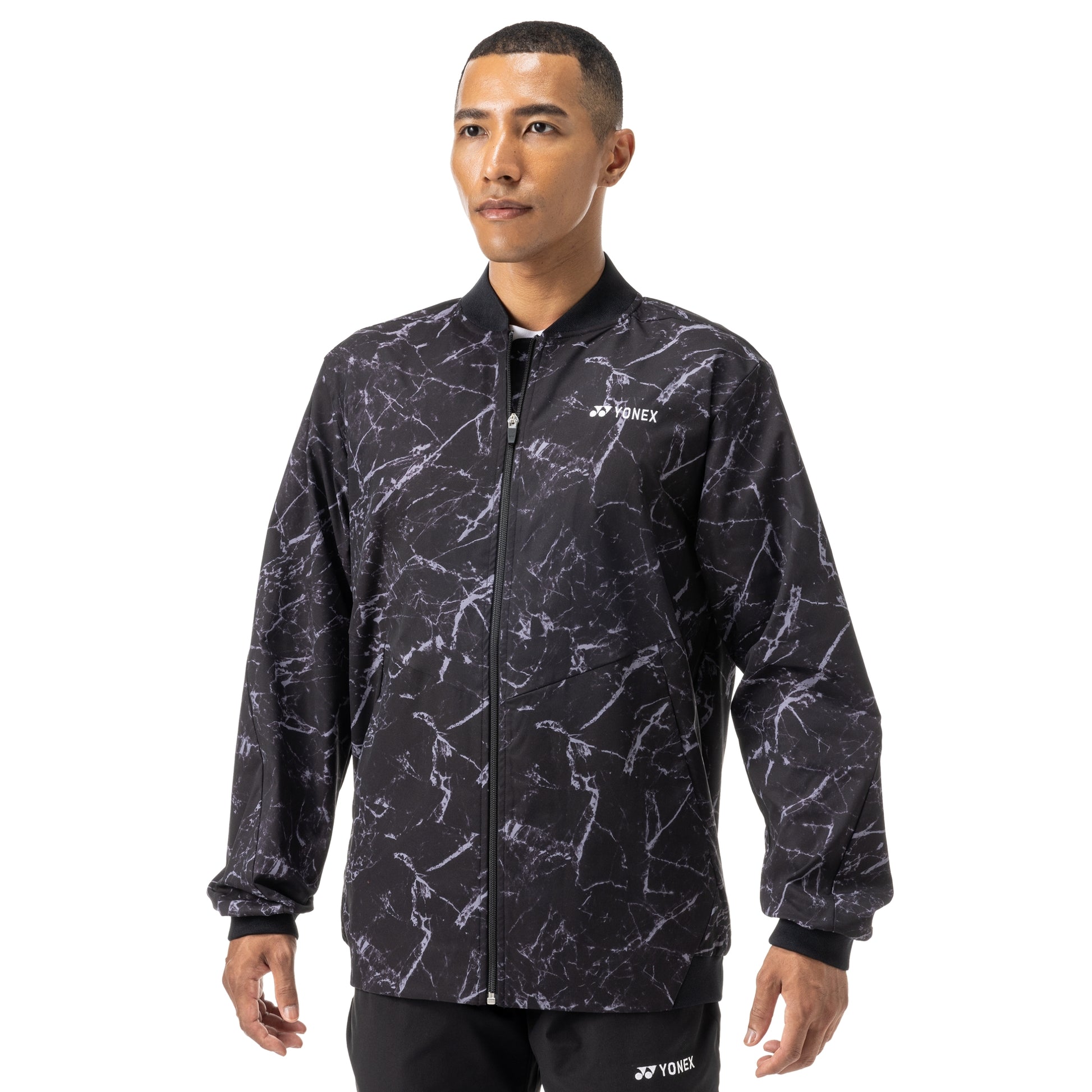 Man wearing a black and gray patterned jacket with Yonex logo on a white background