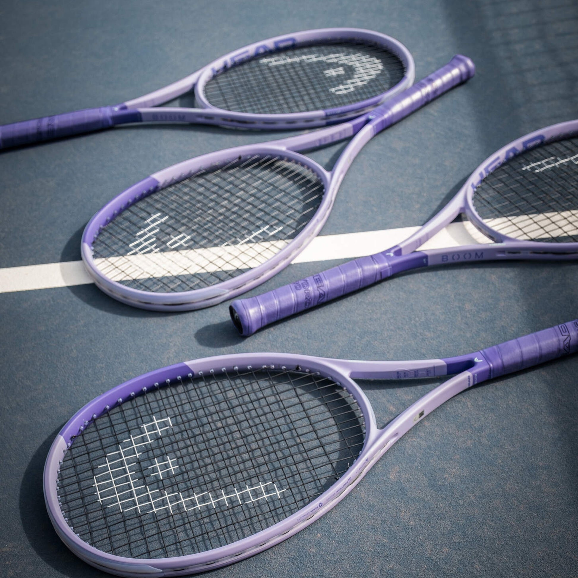 Four purple Head tennis rackets on a tennis court