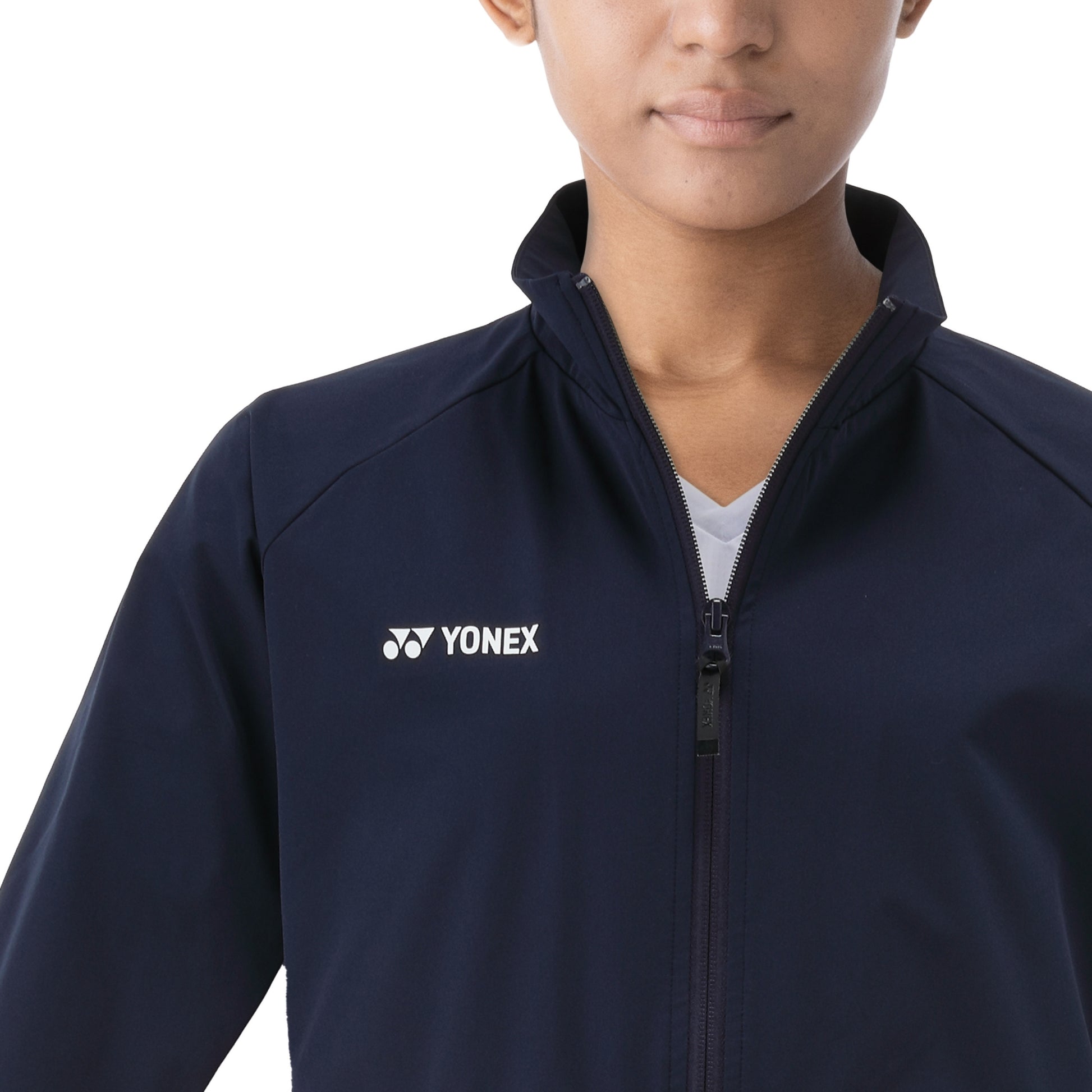 Person wearing a navy blue jacket with Yonex logo on a white background