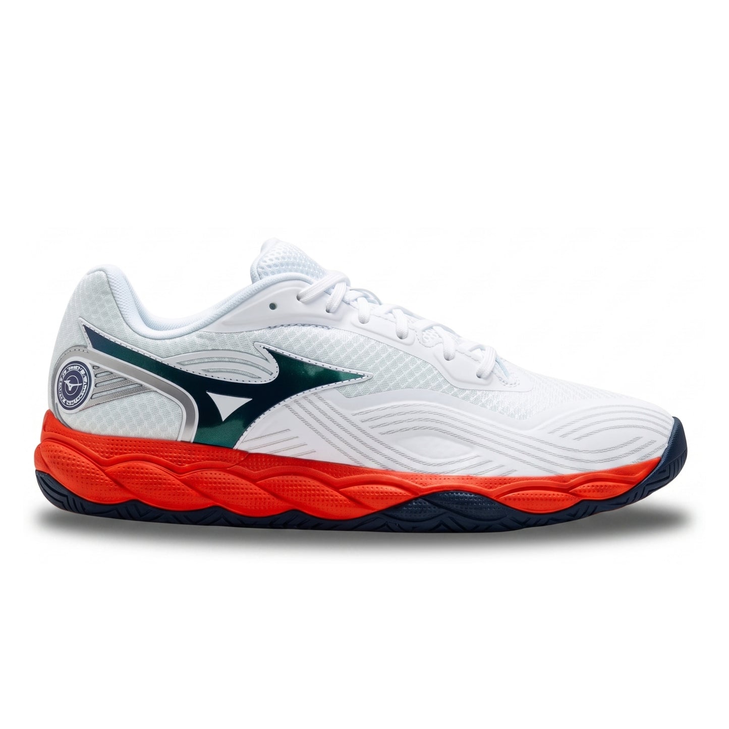 A white Mizuno tennis shoe with a vibrant orange-red midsole, dark teal logo, and navy blue outsole, shown from a side profile on a white background.