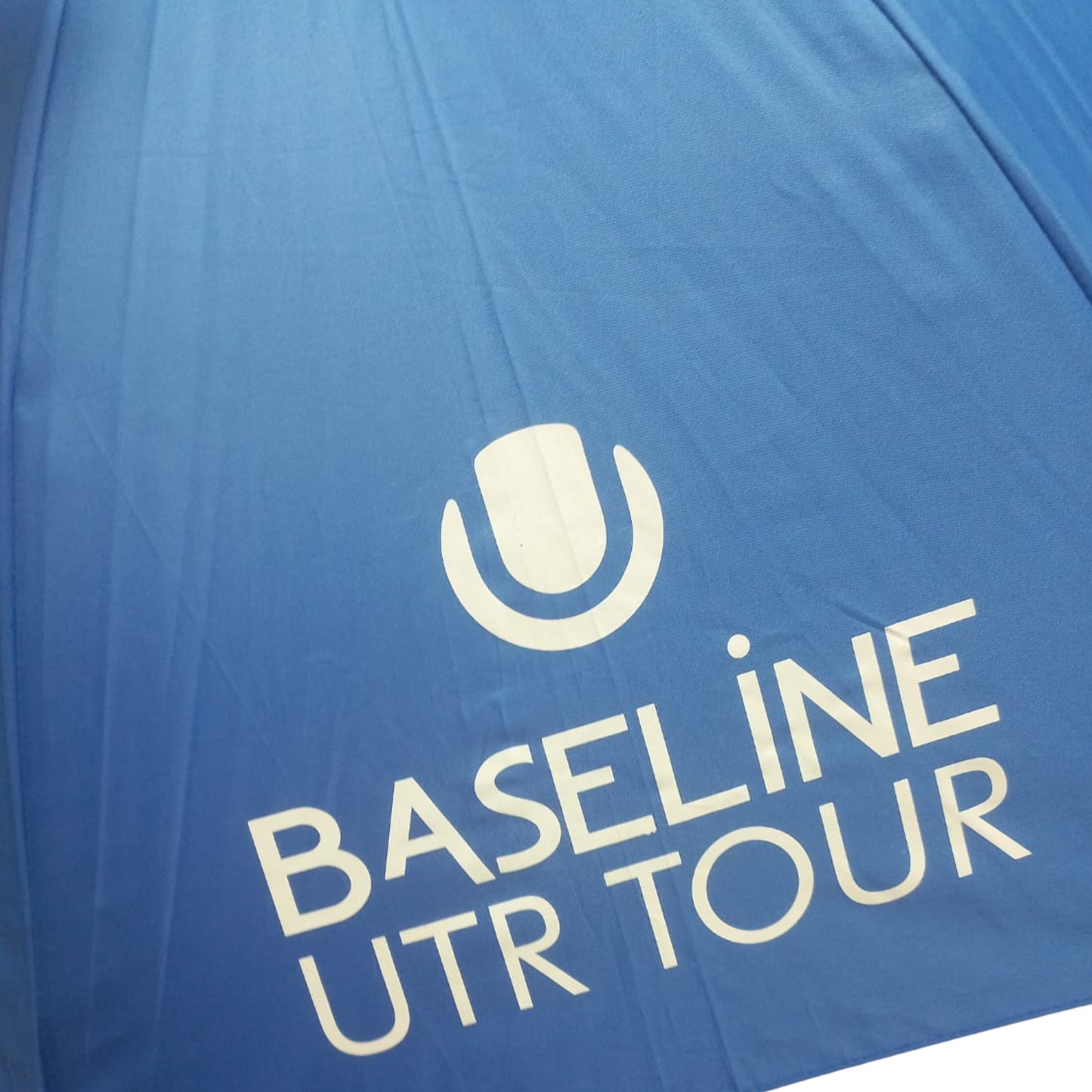 Close-up of a blue umbrella with White Baseline UTR Tour logo