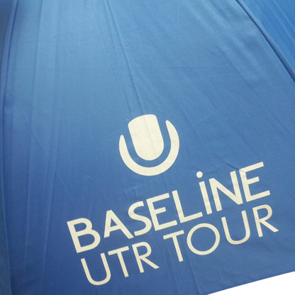 Close-up of a blue umbrella with White Baseline UTR Tour logo