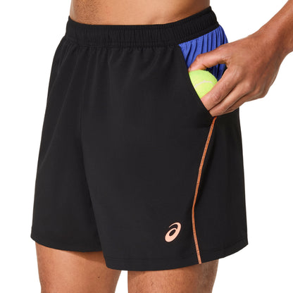 Person wearing black shorts with a brand logo, holding a tennis ball.