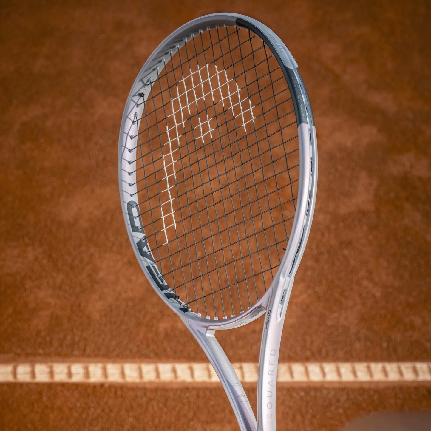 Silver Head tennis racket on a brown tennis court