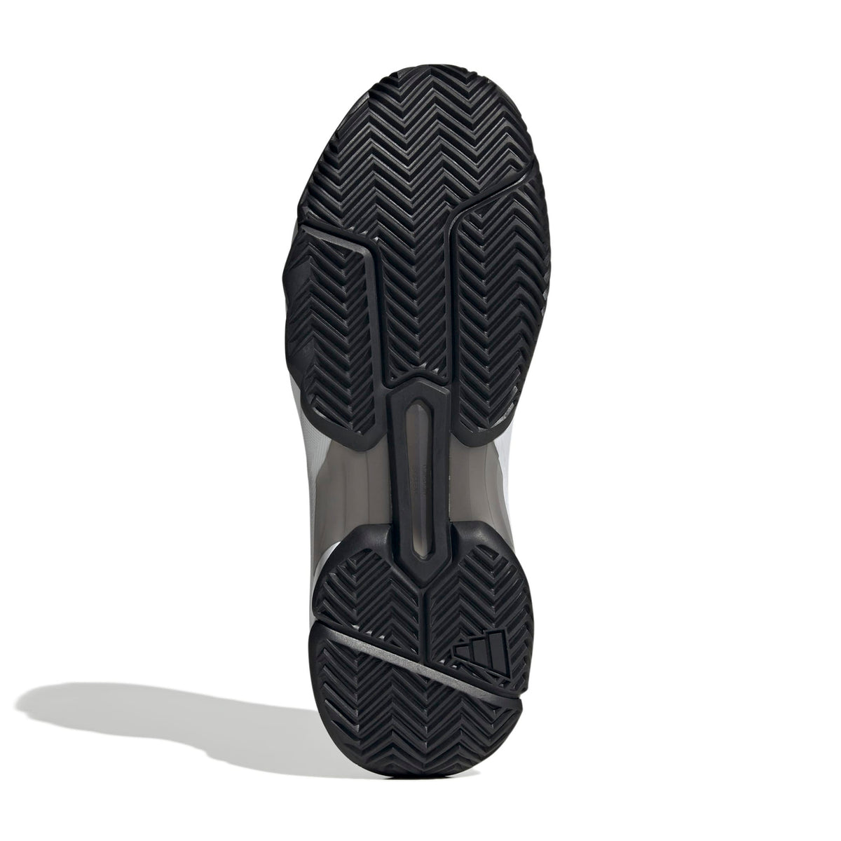The outsole of a tennis shoe, showing a black herringbone tread pattern with a translucent gray midsole section, photographed on a white background with a soft shadow.