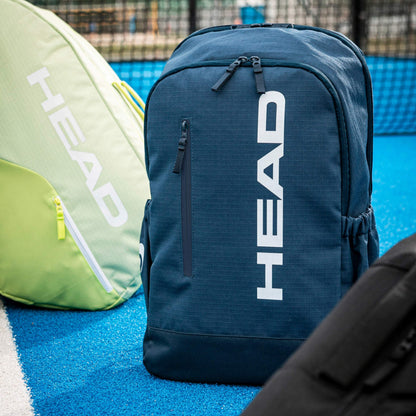 Navy blue tennis backpack with 'HEAD' branding on a tennis court.