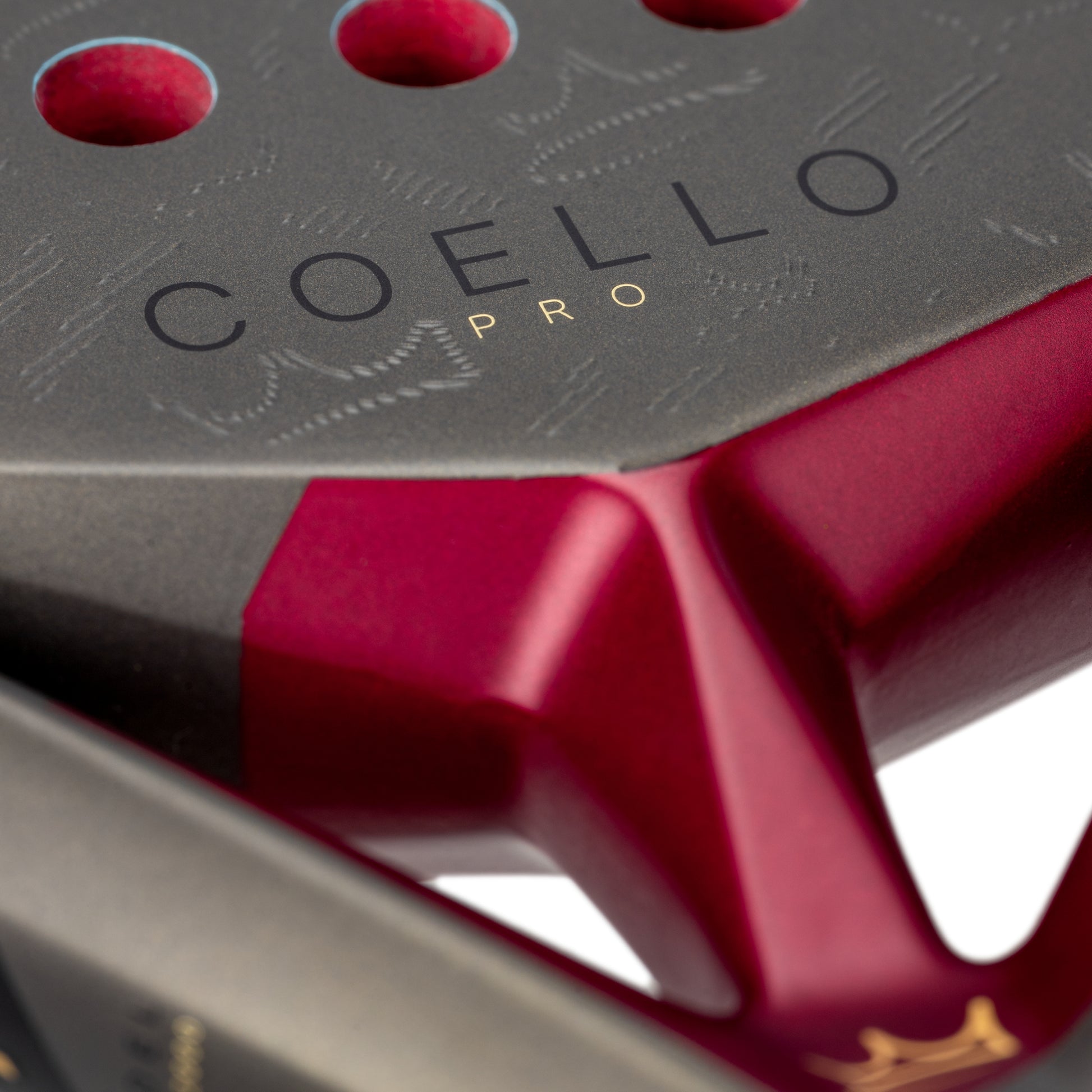 Close-up of a red and black padel racket with 'COELLO PRO' branding.