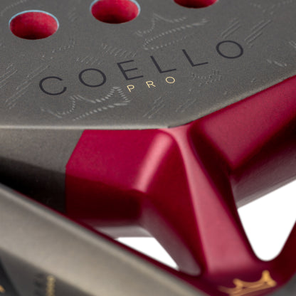 Close-up of a red and black padel racket with 'COELLO PRO' branding.