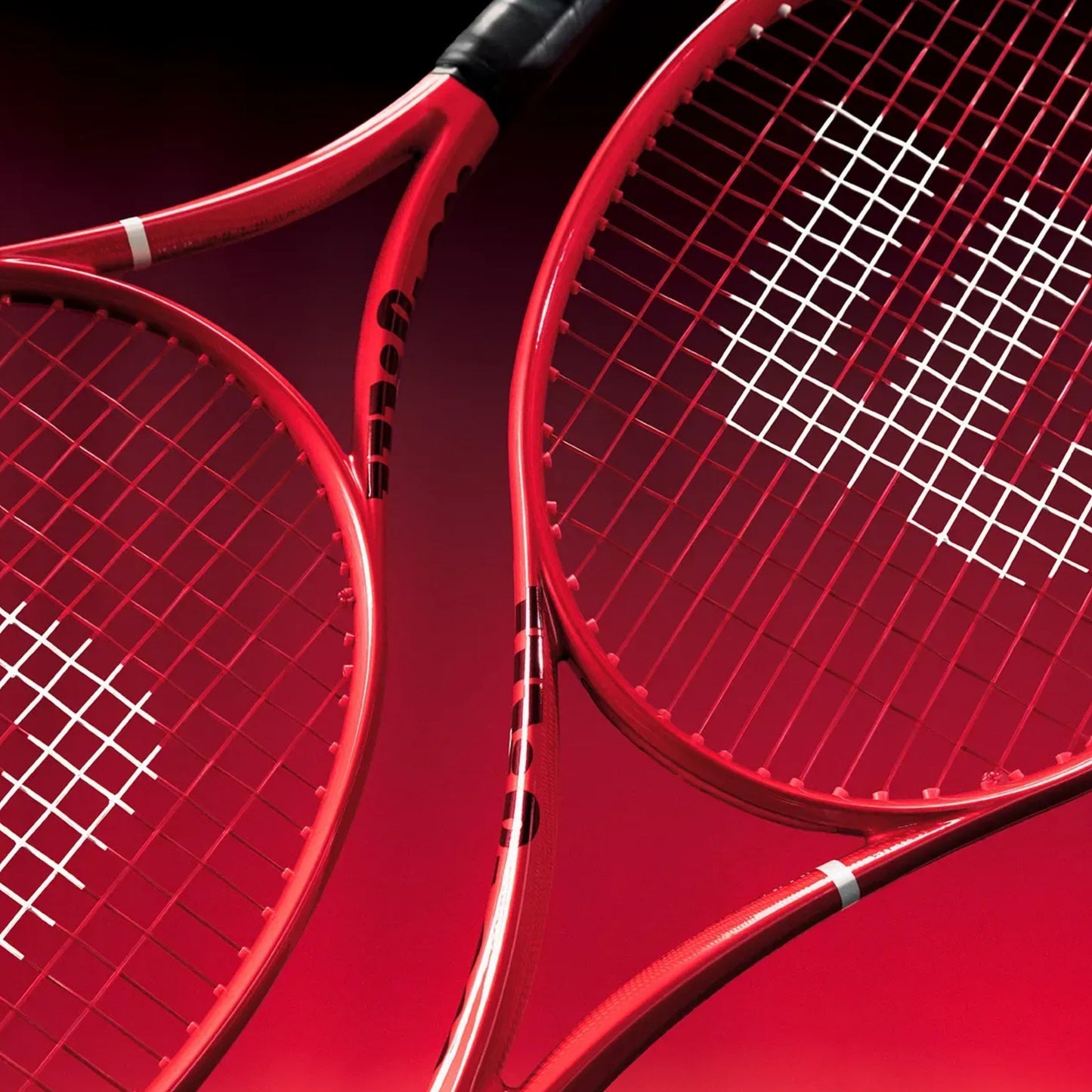 Two red Wilson tennis rackets shown in a close-up studio composition against a dark red background.