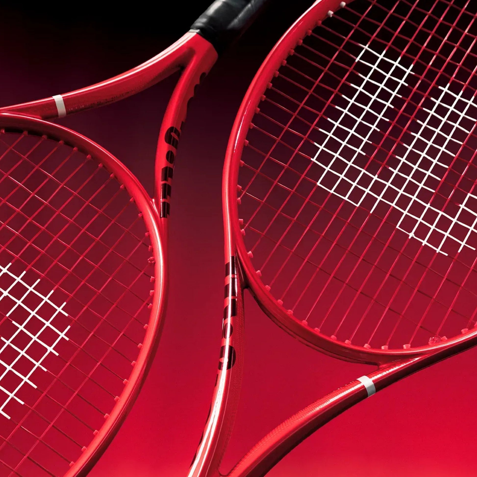 Two red Wilson tennis rackets shown in a close-up studio composition against a dark red background.