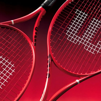 Two red Wilson tennis rackets shown in a close-up studio composition against a dark red background.