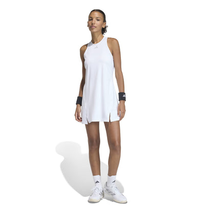 Woman wearing a white sleeveless adidas dress and white sneakers on a white background