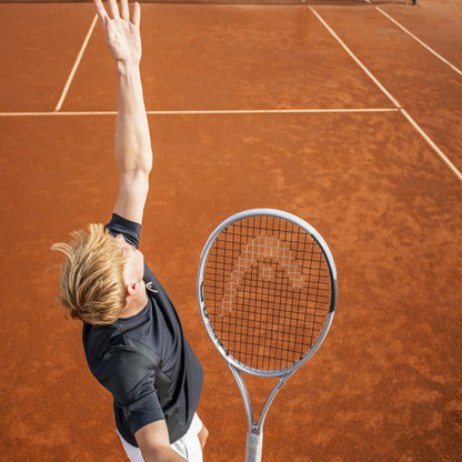 Person playing with a Head tennis racket on a clay court with a racket