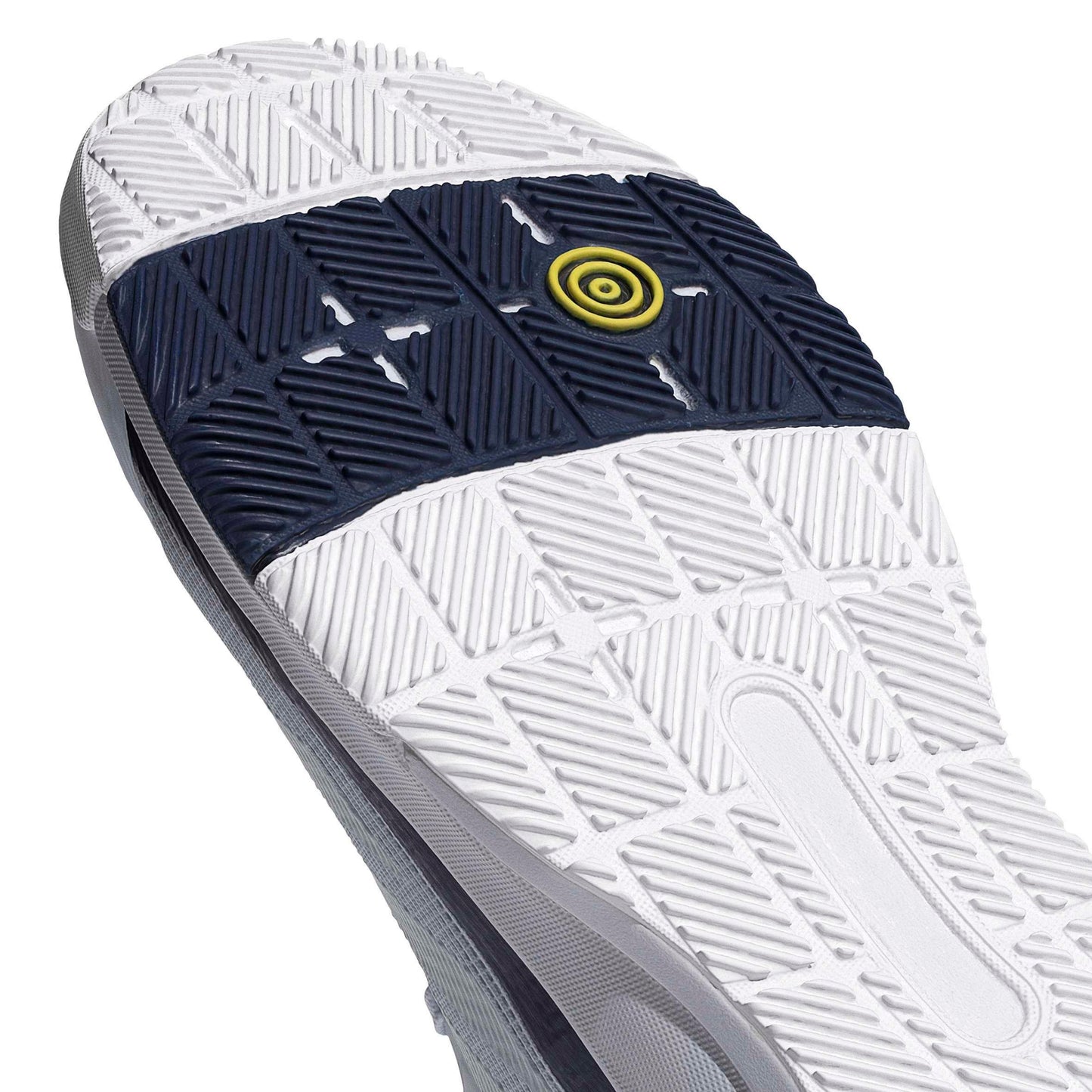 Close-up of a padel shoe showing a white textured outsole with a dark navy blue grip section and a small yellow circular logo.