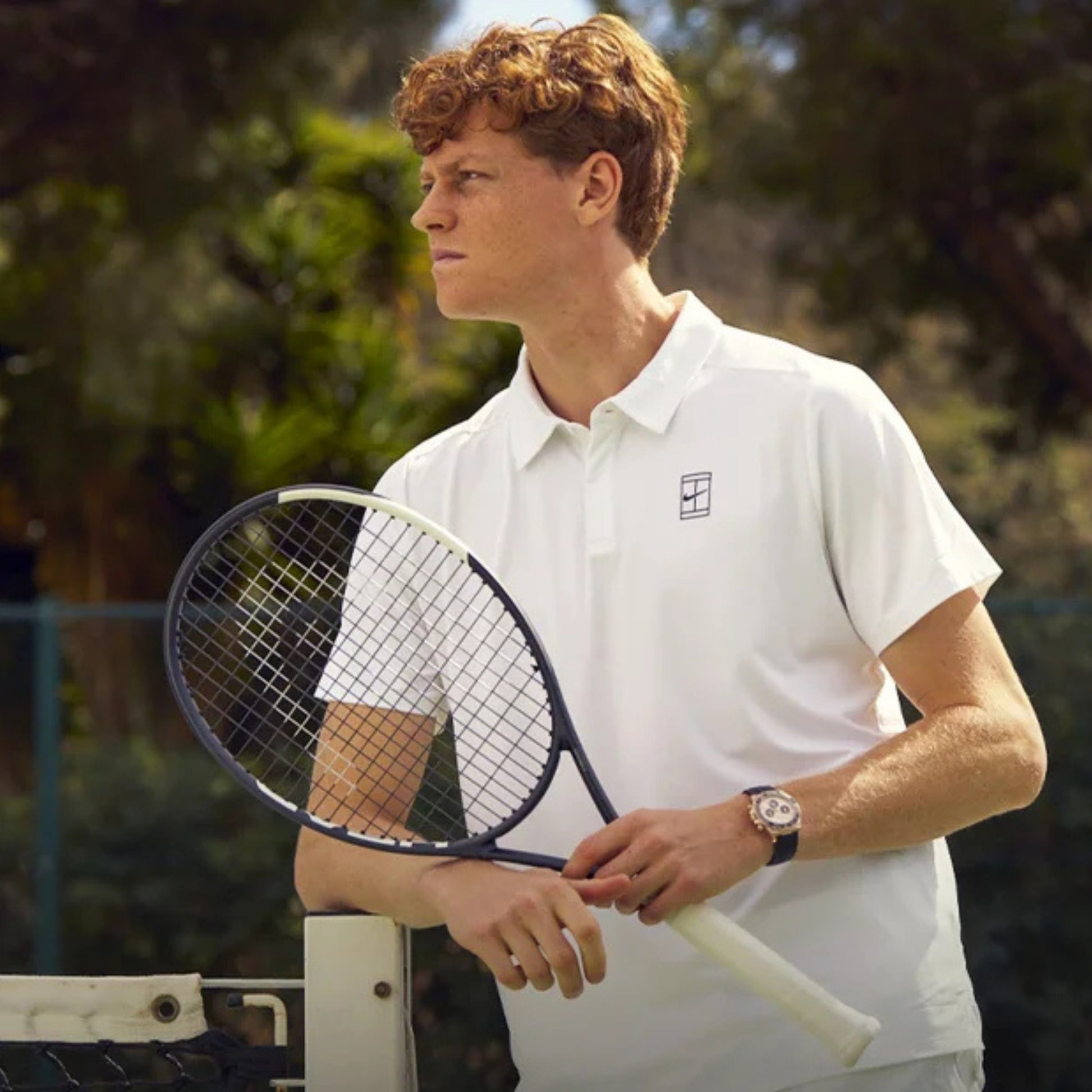 Person holding a tennis racket outdoors with a blurred background