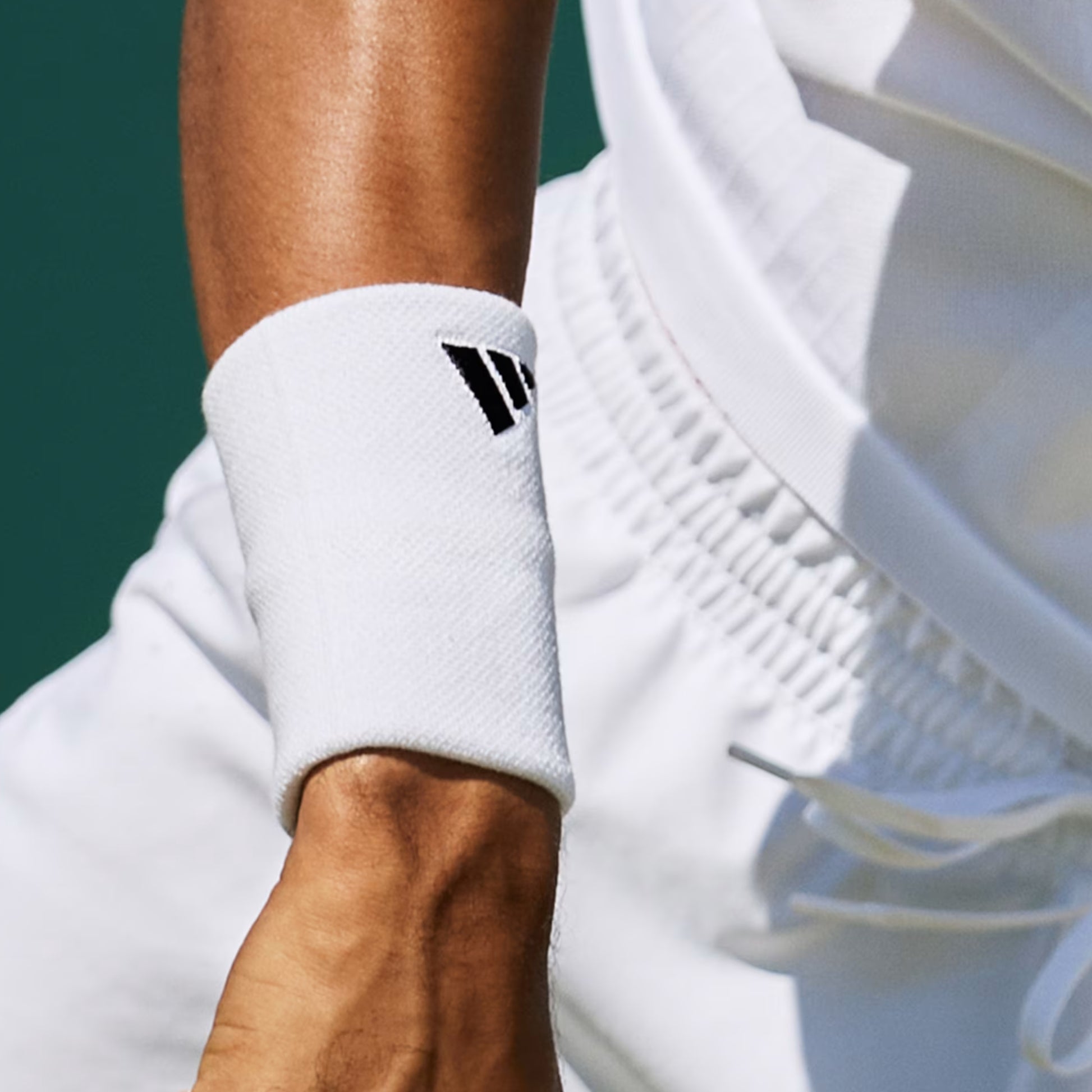 Close-up of a person wearing a white wristband with a logo on a blurred background