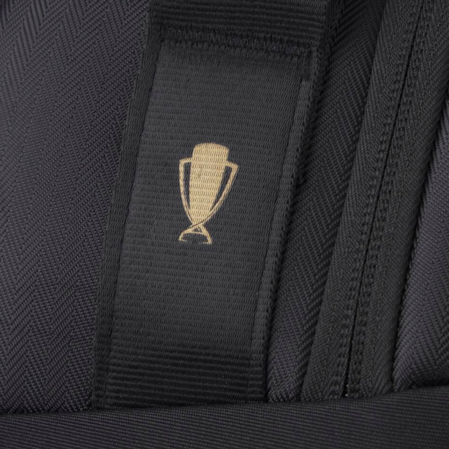 Close-up of a black tennis bag with a gold emblem on a textured background